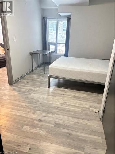 This room features light-toned wood-style flooring and a window with curtains - 275 Larch Street Unit# 108, Waterloo, ON - Indoor