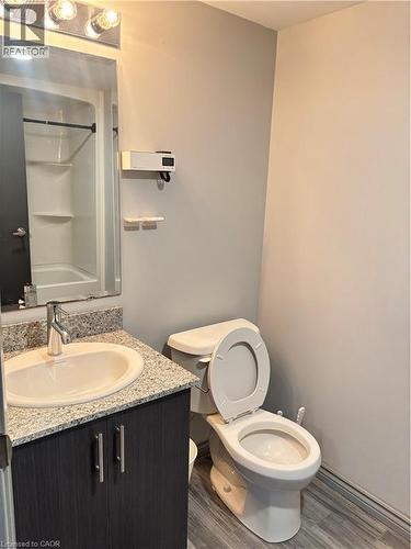 Bathroom featuring a granite-style countertop vanity with a chrome faucet, a toilet, and a shower with a black shower curtain rod - 275 Larch Street Unit# 108, Waterloo, ON - Indoor Photo Showing Bathroom