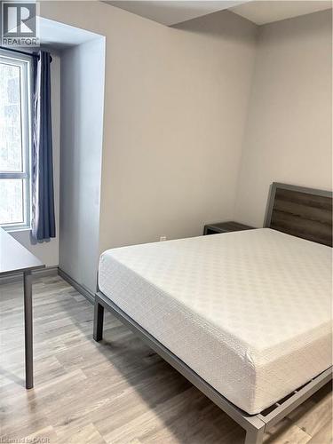 The room features light wood-look flooring and a window with curtains - 275 Larch Street Unit# 108, Waterloo, ON - Indoor