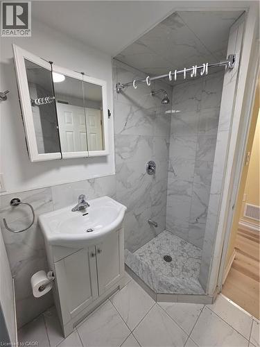 The bathroom features a corner shower with marble-look tile walls and a hexagonal tile floor - 62 Richwill Road Unit# Lower, Hamilton, ON - Indoor Photo Showing Bathroom