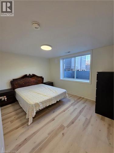 This room features light-toned wood flooring, a window with horizontal blinds, and a ceiling-mounted light fixture - 62 Richwill Road Unit# Lower, Hamilton, ON - Indoor Photo Showing Bedroom