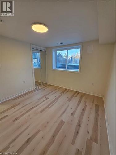 This room features light-toned wood flooring, a window offering natural light, and a ceiling light fixture - 62 Richwill Road Unit# Lower, Hamilton, ON - Indoor Photo Showing Other Room