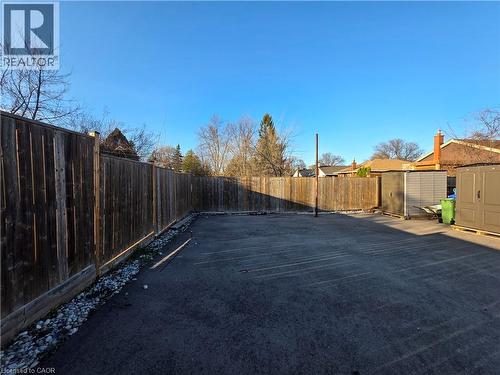 The property features a fenced outdoor area with an asphalt surface - 62 Richwill Road Unit# Lower, Hamilton, ON - Outdoor