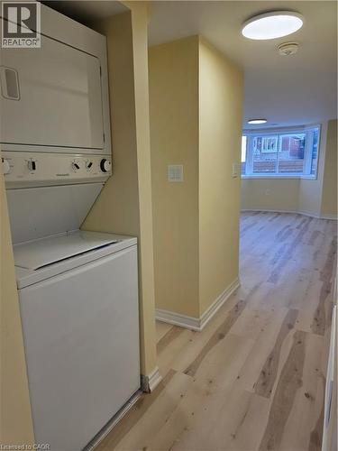 This property includes a stacked washer and dryer unit, light-toned walls, and wood-look flooring - 62 Richwill Road Unit# Lower, Hamilton, ON - Indoor Photo Showing Laundry Room