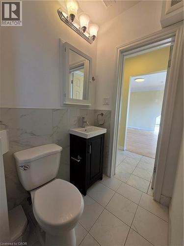 Bathroom featuring a white toilet, a dark vanity with an integrated sink, and a mirrored medicine cabinet - 62 Richwill Road Unit# Upper, Hamilton, ON - Indoor Photo Showing Bathroom