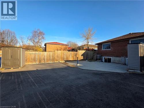The property features a spacious paved area, a wooden fence, and a concrete patio - 62 Richwill Road Unit# Upper, Hamilton, ON - Outdoor
