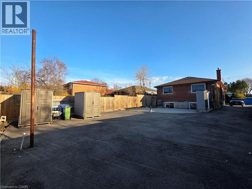 The property features an extensive paved area and a brick exterior with a visible chimney - 62 Richwill Road Unit# Upper, Hamilton, ON - Outdoor