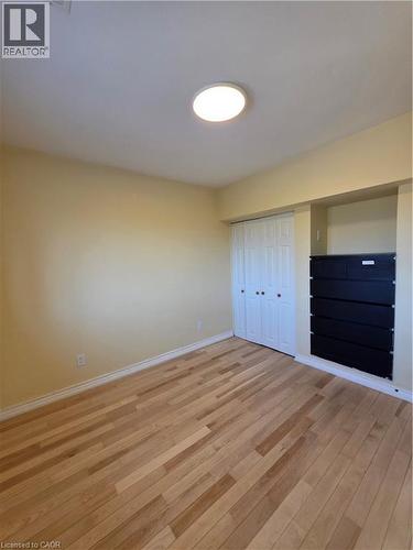 This inviting room features light-toned hardwood flooring, a ceiling-mounted light fixture, and a built-in storage unit with black drawers - 62 Richwill Road Unit# Upper, Hamilton, ON - Indoor Photo Showing Other Room