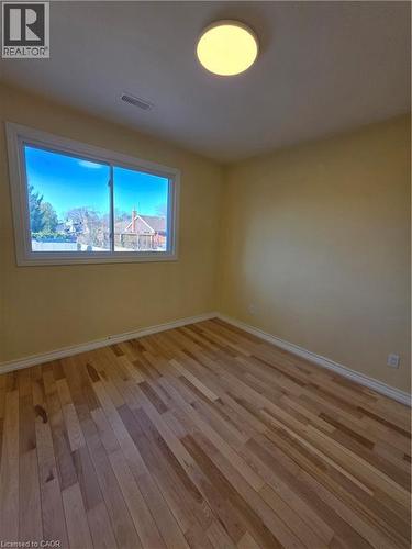 This room features hardwood flooring, a bright window providing natural light, and a ceiling-mounted light fixture - 62 Richwill Road Unit# Upper, Hamilton, ON - Indoor Photo Showing Other Room