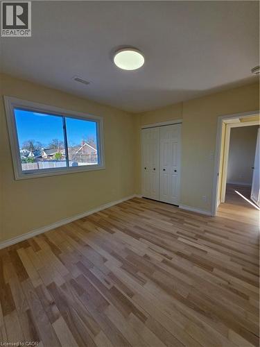 This room features light-toned hardwood flooring, a large window providing views of the surrounding area, and a white bi-fold closet - 62 Richwill Road Unit# Upper, Hamilton, ON - Indoor Photo Showing Other Room