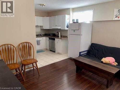The kitchen features white cabinetry, a stainless steel dishwasher, and tiled flooring - 65 Cardill Crescent Unit# B, Waterloo, ON - Indoor Photo Showing Kitchen