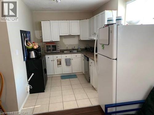 The kitchen features white cabinetry, a sink, and a refrigerator - 65 Cardill Crescent Unit# B, Waterloo, ON - Indoor Photo Showing Kitchen
