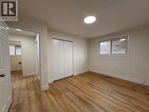 This room features wood flooring, a window providing natural light, and a closet with bifold doors - 23 Arrowhead Crescent Unit# Upper, Kitchener, ON - Indoor Photo Showing Other Room