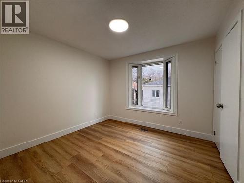 The interior space features light-colored walls, hardwood flooring, and a contemporary ceiling light fixture - 23 Arrowhead Crescent Unit# Upper, Kitchener, ON - Indoor Photo Showing Other Room