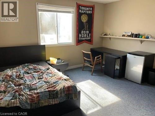 Bedroom with light carpet, freestanding refrigerator, and an office area - 65 Cardill Crescent Unit# A, Waterloo, ON - Indoor Photo Showing Bedroom