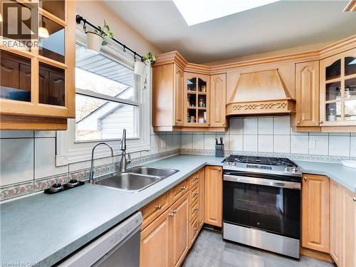Kitchen featuring glass insert cabinets, stainless steel appliances, tasteful backsplash, and custom range hood - 9183 Silver Street, Caistor Centre, ON - Indoor Photo Showing Kitchen With Double Sink