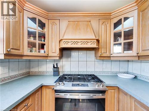 Kitchen featuring glass insert cabinets, stainless steel gas range oven, tasteful backsplash, premium range hood, and light countertops - 9183 Silver Street, Caistor Centre, ON - Indoor Photo Showing Kitchen