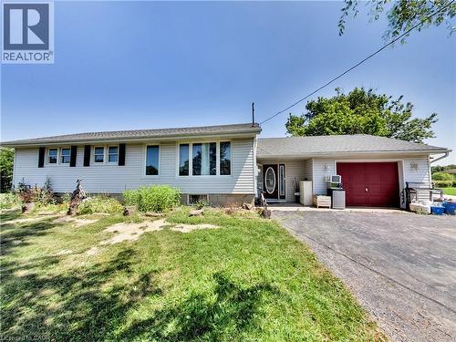 Ranch-style exterior with light-colored siding, contrasting black shutters, and a dark asphalt driveway - 9183 Silver Street, Caistor Centre, ON - Outdoor