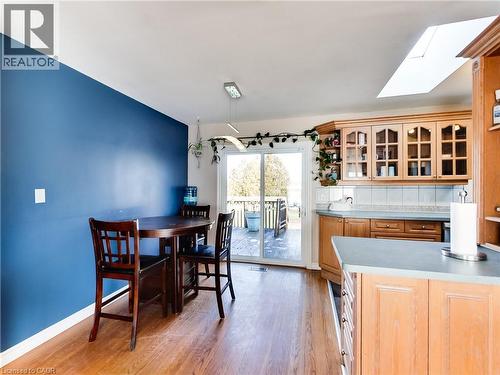 Kitchen area featuring wood-finish flooring, a vibrant blue accent wall, a skylight, and light-toned cabinetry with glass-front uppers - 9183 Silver Street, Caistor Centre, ON - Indoor