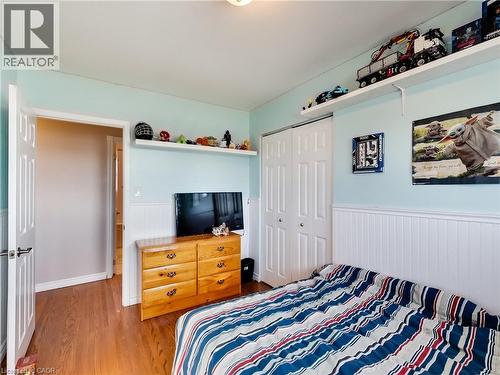 Interior room featuring wood-finish flooring, light blue walls, and white wainscoting - 9183 Silver Street, Caistor Centre, ON - Indoor Photo Showing Bedroom