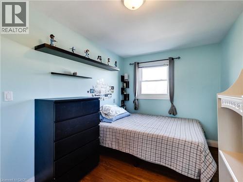 Hardwood-finish flooring, built-in shelving, white trim window, neutral ceiling light fixture - 9183 Silver Street, Caistor Centre, ON - Indoor Photo Showing Bedroom