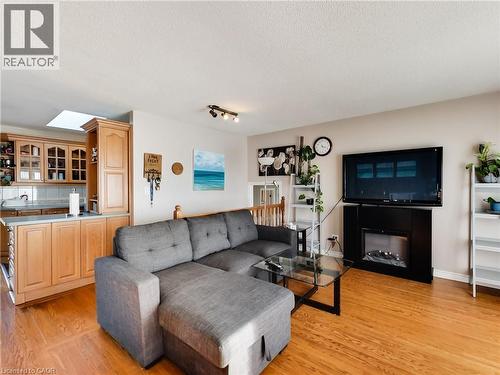 Living room featuring light wood-type flooring, a textured ceiling, and a fireplace - 9183 Silver Street, Caistor Centre, ON - Indoor Photo Showing Living Room
