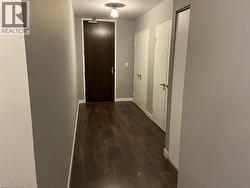 Hallway featuring dark wood flooring, light grey walls, and white trim - 