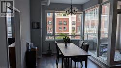The dining area features dark wood flooring, a window with a roller blind, and a glass-paneled door leading to a balcony - 