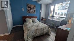 This room features rich hardwood flooring, an accent wall with a unique shade of blue, and a large window with horizontal blinds - 