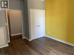 This room features wood-look flooring, white baseboards, a white closet with gold hardware, and walls painted in a combination of yellow and gray tones - 