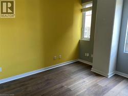 This room offers dark wood flooring, a window with blinds, and walls painted in a combination of yellow and gray - 