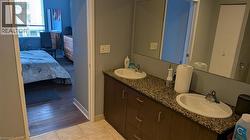 Bathroom vanity featuring a double sink with granite countertops and under-sink cabinetry - 