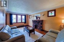Living area featuring a brick fireplace with wood mantel, hardwood flooring, and multiple windows - 