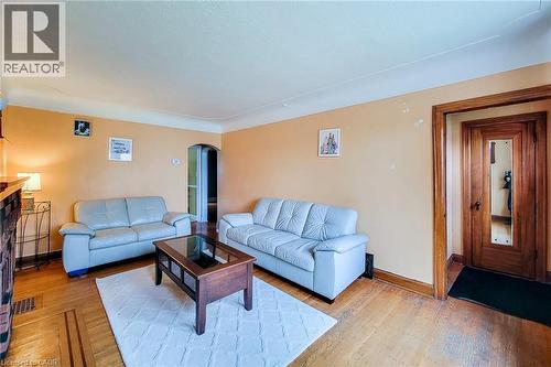 Hardwood flooring with inlaid details, complemented by a decorative wood-framed entryway with a full-length mirror - 66 Cline Avenue Unit# Main Floor, Hamilton, ON - Indoor Photo Showing Living Room