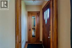 Entryway featuring a wood-panel door with decorative glass inserts, natural wood trim, and wood-finish flooring - 