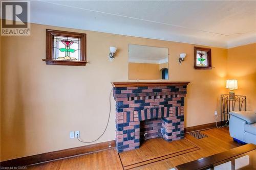 Brick fireplace with a wood-finish mantel, flanked by two wall sconces and two stained-glass windows - 66 Cline Avenue Unit# Main Floor, Hamilton, ON - Indoor Photo Showing Other Room
