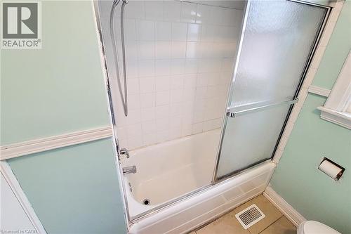 Bathtub with white subway tile surround and frosted glass sliding shower doors - 66 Cline Avenue Unit# Main Floor, Hamilton, ON - Indoor Photo Showing Bathroom