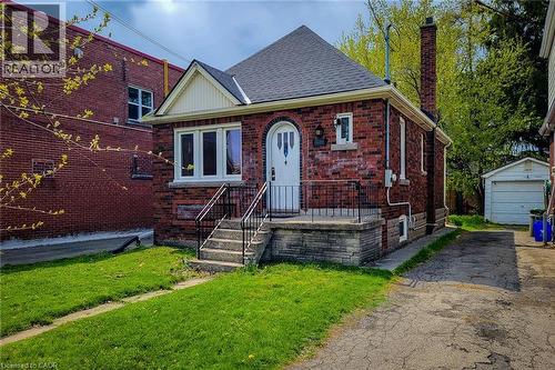 Brick exterior with white trim, arched entry door, a prominent front chimney, and a detached garage - 66 Cline Avenue Unit# Main Floor, Hamilton, ON - Outdoor
