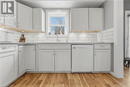 The kitchen features light-colored cabinetry, a white subway tile backsplash, and a window above the sink - 99 Robins Avenue, Hamilton, ON - Indoor Photo Showing Kitchen