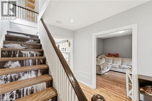 The property features a staircase with wood treads and a white baluster railing, complemented by a distinctive riser design - 99 Robins Avenue, Hamilton, ON - Indoor Photo Showing Other Room