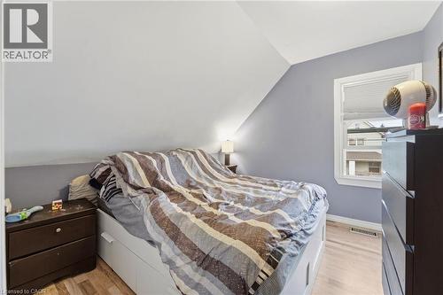 This bedroom features light wood flooring, a window with blinds, and a built-in bed frame with storage - 99 Robins Avenue, Hamilton, ON - Indoor Photo Showing Bedroom