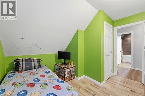 This room features hardwood flooring and a brightly painted wall - 99 Robins Avenue, Hamilton, ON - Indoor Photo Showing Bedroom