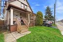 The property features a two-story exterior with light-colored siding and brown trim, a front porch with wooden steps and railings, and a small front yard with a lawn - 99 Robins Avenue, Hamilton, ON  - Outdoor With Deck Patio Veranda 