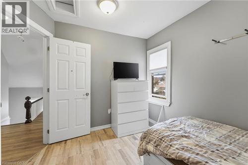 Room featuring light wood-style flooring, a window providing exterior views, and a white paneled door - 99 Robins Avenue, Hamilton, ON - Indoor Photo Showing Bedroom