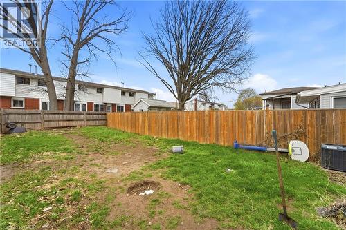 The property features an extensive yard with a wooden fence and mature trees - 99 Robins Avenue, Hamilton, ON - Outdoor