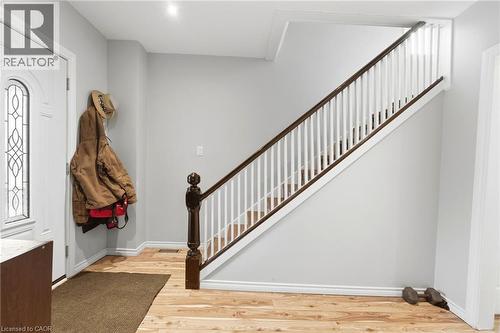 Entryway featuring hardwood flooring, a white door with decorative glass, and a staircase with white spindles and dark wood handrails - 99 Robins Avenue, Hamilton, ON - Indoor Photo Showing Other Room