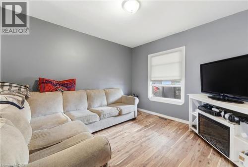 The interior space features hardwood flooring, neutral grey walls, and a window providing natural light - 99 Robins Avenue, Hamilton, ON - Indoor Photo Showing Living Room