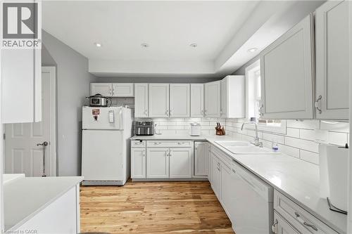 Well-appointed kitchen featuring hardwood floors, white cabinetry, white subway tile backsplash, white countertops, and recessed lighting - 99 Robins Avenue, Hamilton, ON - Indoor Photo Showing Kitchen
