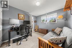 The room features carpeted flooring, a window with decorative curtains, and light gray walls - 