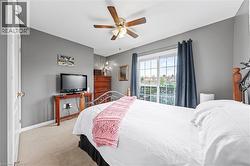 This room features light-colored carpeting, a ceiling fan, and a sliding glass door providing natural light and access to an outdoor area - 